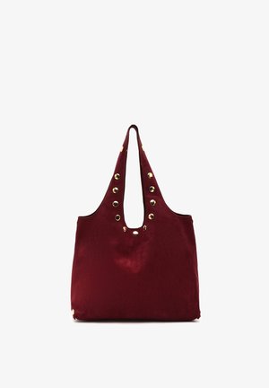 Grand sac cabas bordeaux avec des anses larges et des clous dorés décoratifs le long des bords et des ouvertures des anses.