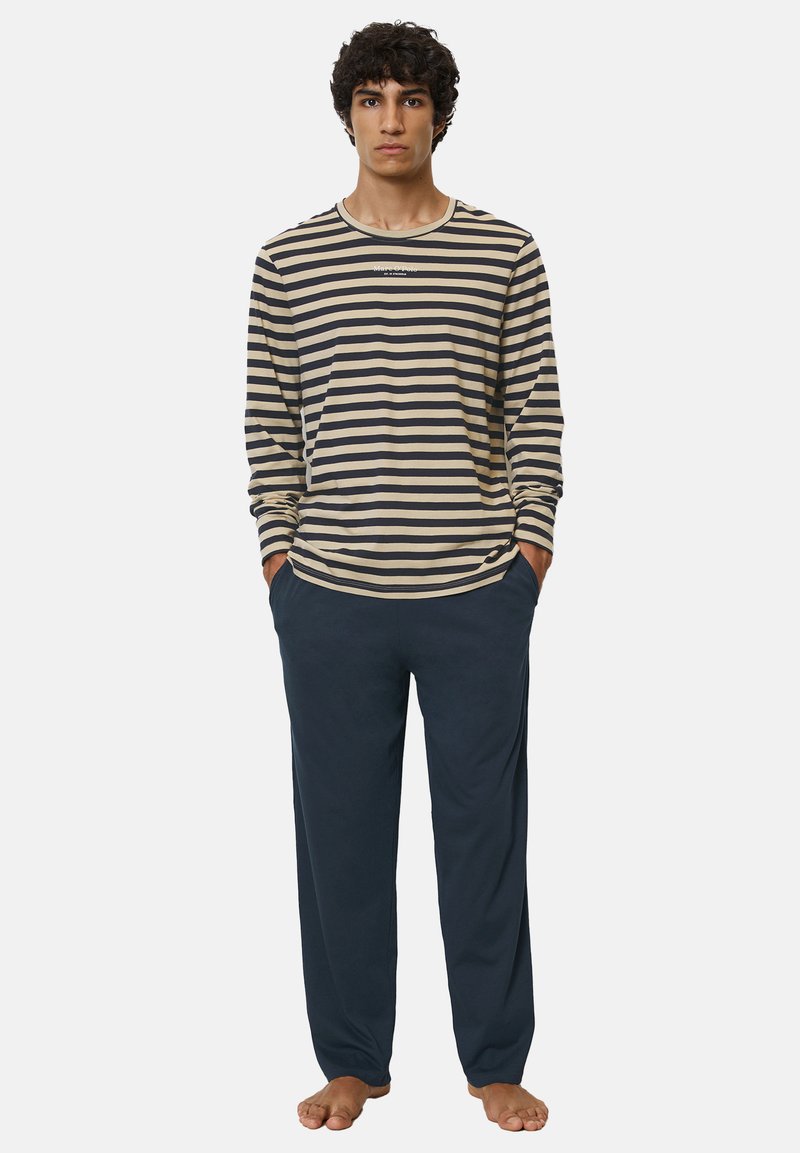 Langärmliges gestreiftes Shirt in Creme und Marine, kombiniert mit marinen Hosen. Das Shirt hat einen runden Ausschnitt und eine lockere Passform.