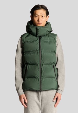 Groene geïsoleerde donsvest met een oversized kraag en ritszakken aan de zijkant, gedragen over een grijze sweatshirt, wat warmte en functionaliteit toevoegt.