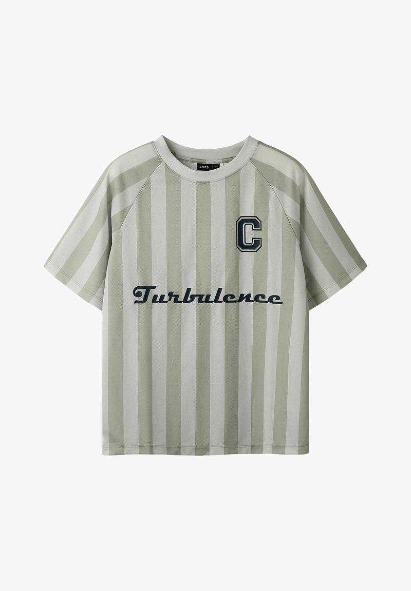 Chemise à manches courtes, beige et blanche à rayures verticales, avec un patch "C" sur la poitrine et le texte "Turbulence" en écriture cursive noire sur le devant.
