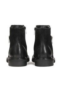 Botines de cuero negro con un acabado suave, que cuentan con cremalleras a los lados, una suela resistente y elementos de diseño minimalistas.