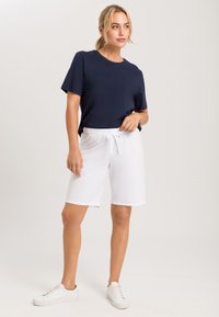 Marineblauw T-shirt met korte mouwen gecombineerd met witte shorts met elastische taille en witte sneakers, met een casual en comfortabele uitstraling.