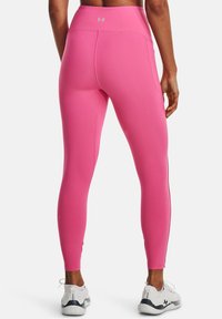 Fuksjowe legginsy z wysokim pasem, gładką teksturą i dopasowanym krojem. Posiadają logo Under Armour z tyłu oraz przylegający krój na całej długości.