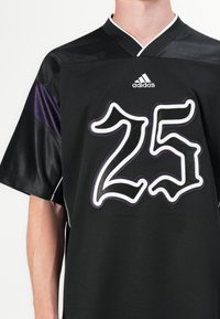 Fekete sportmez rövid ujjakkal, lila kiegészítésekkel, fehér gallérral és nagy, fehér kerettel ellátott "25"-ös számokkal stílusos betűtípussal.