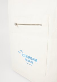 Cotton tote bag in white with a front zip pocket. Features blue text "ICECREAM PLEASE" and water droplet designs. Smooth texture.