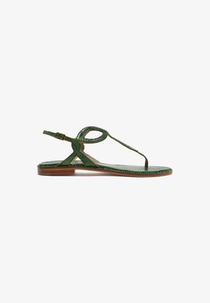 Sandale plate en cuir vert avec bride en T, boucle à la cheville et semelle marron, vue de profil sur fond blanc.