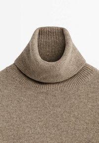 Beżowy wełniany sweter z wysokim kołnierzem, dziany, z ryflowanym kołnierzem i dolną krawędzią, wyeksponowany na białym tle.