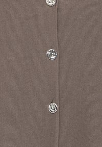 Brun stickad cardigan med fyra metallknappar längs framplåten. Tyget har en texturerad finish med en lätt stretch.