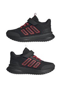 Zapatillas deportivas negras con acentos rojos, parte superior de malla, una correa de gancho y bucle, y distintiva marca de tres rayas en el lateral. Suela de goma.