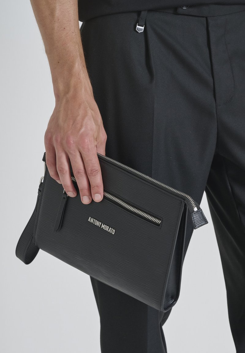 Clutch negro texturizado con un bolsillo con cremallera en la parte frontal y herrajes de acero inoxidable. Presenta el nombre de la marca "ANTONY MORATO" grabado en la parte frontal.