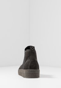 Bottine en daim gris foncé avec une semelle en caoutchouc texturée, des panneaux latéraux élastiques et une boucle circulaire à l'arrière.