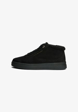 Sneaker mid-top in suede nero con una superficie testurizzata, suola in gomma piatta e morbida fodera in shearling attorno al collare. Dettagli del logo in oro.