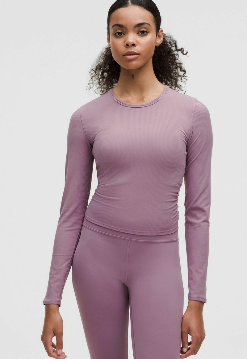 Tricou sportiv mauve cu mânecă lungă, cu textură cordată, design ajustat și gât rotund, asociat cu colanți asortați, ajustați.