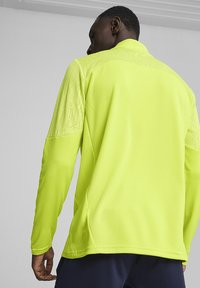 Langsleeve jack in fel neon geel. Bevat textuurstof op de schouders en rug. Gladde textuur, aangesloten ontwerp en neutrale accenten.