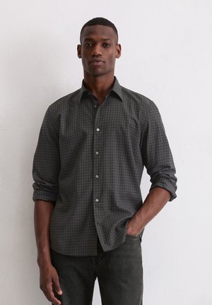 Cămașă button-up gri închis cu un model cu pătrățele, mâneci lungi răsfrânte până la coate și nasturi gri deschis. Purtați cu blugi negri.