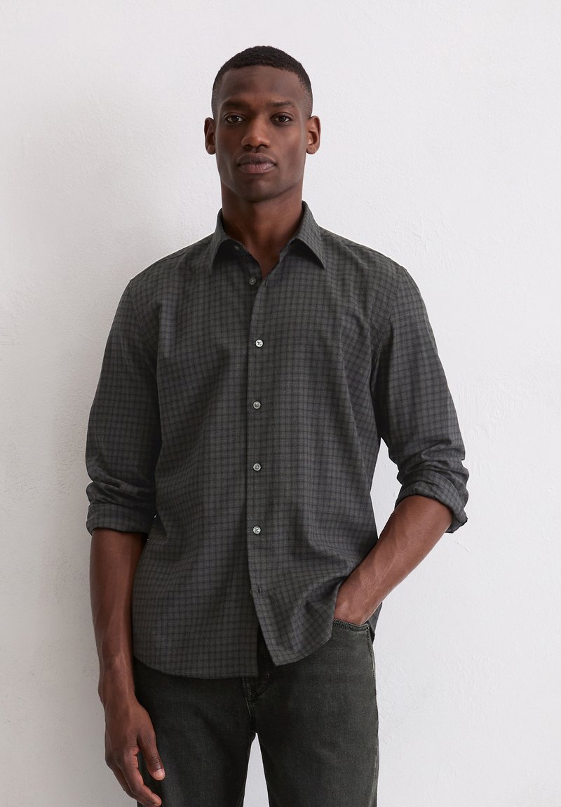Donkergrijze button-up shirt met een geruit patroon, lange mouwen opgerold tot de ellebogen, en lichtgrijze knopen. Draag met donkere jeans.