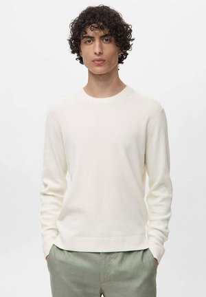 White ribbed sweater with long sleeves, round neckline, and a soft texture, paired with light green trousers. Simple and modern design.