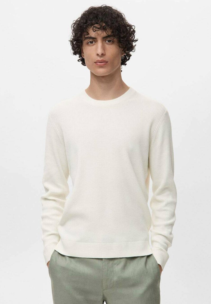 Pull en maille blanche à rayures, à manches longues, avec un col rond et une texture douce, associé à un pantalon vert clair. Design simple et moderne.