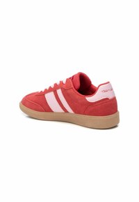Zapatillas de ante rojo con acentos en rosa y dos rayas blancas. Punta redonda y suela de goma texturizada, con un collar acolchado y diseño de cordones.