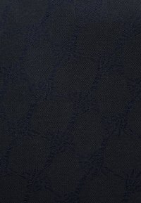 Μαύρο υφασμάτινο με υφή που παρουσιάζει διακριτικό γεωμετρικό μοτίβο με αλληλοσυνδεόμενα σχήματα, προσφέροντας βάθος μέσω ποικιλίας αποχρώσεων σκούρου μπλε.