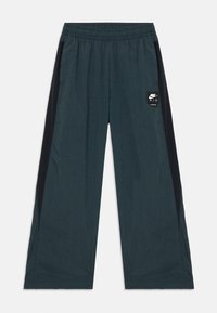 Mörkblå byxor i sweatpantsstil med svarta sidopaneler, elastisk midja, lös passform och en liten Nike Air-logotyp framtill.