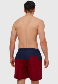 Røde og marineblå svømmeshorts med elastisk talje, med en baglomme med knapdetalje og glat tekstur.