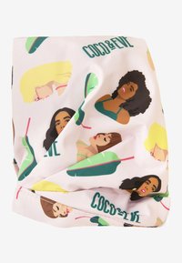 Tissu multicolore présentant des visages illustrés avec diverses coiffures sur un fond rose clair, rehaussé de feuilles vertes et de texte.