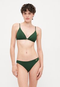 Ensemble de bikini vert à côtes comprenant un haut triangulaire avec des bretelles ajustables et un bas taille basse assorti, le tout agrémenté de subtils accents dorés.