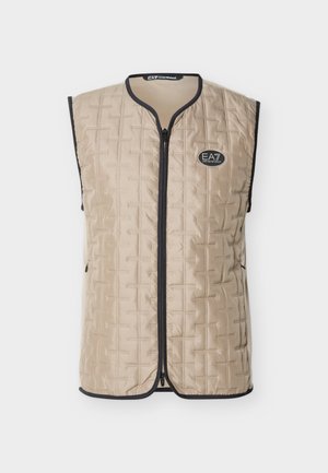 Beige quiltet vest uten ermer med svart kanting, glidelås foran og EA7 Emporio Armani-logo på brystet, vist på ensfarget bakgrunn.