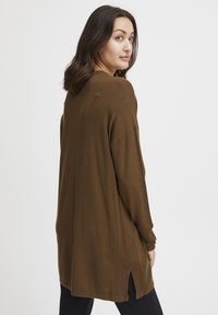 Pulover tricotat maro cu o croială lejeră, mâneci lungi, textură canalată, fante pe laturi și un tiv rotund. Modelul este prezentat din spate.
