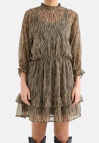 Durchsichtiges, zebra-gestreiftes Kleid in Beige und Schwarz, mit einem Rüsche-Saum, langen Ärmeln und einem hohen Kragen mit einem rüschenden Rand.