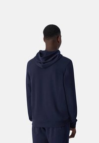 Navy hoodie met een relaxte pasvorm, zachte stof en geribde manchetten. Het ontwerp heeft een dubbele capuchon en een strakke silhouet.
