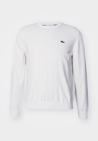 Vit bomullströja med rund halsringning och långa ärmar, med en liten broderad logotyp på bröstet samt ribbade muddar och fåll.