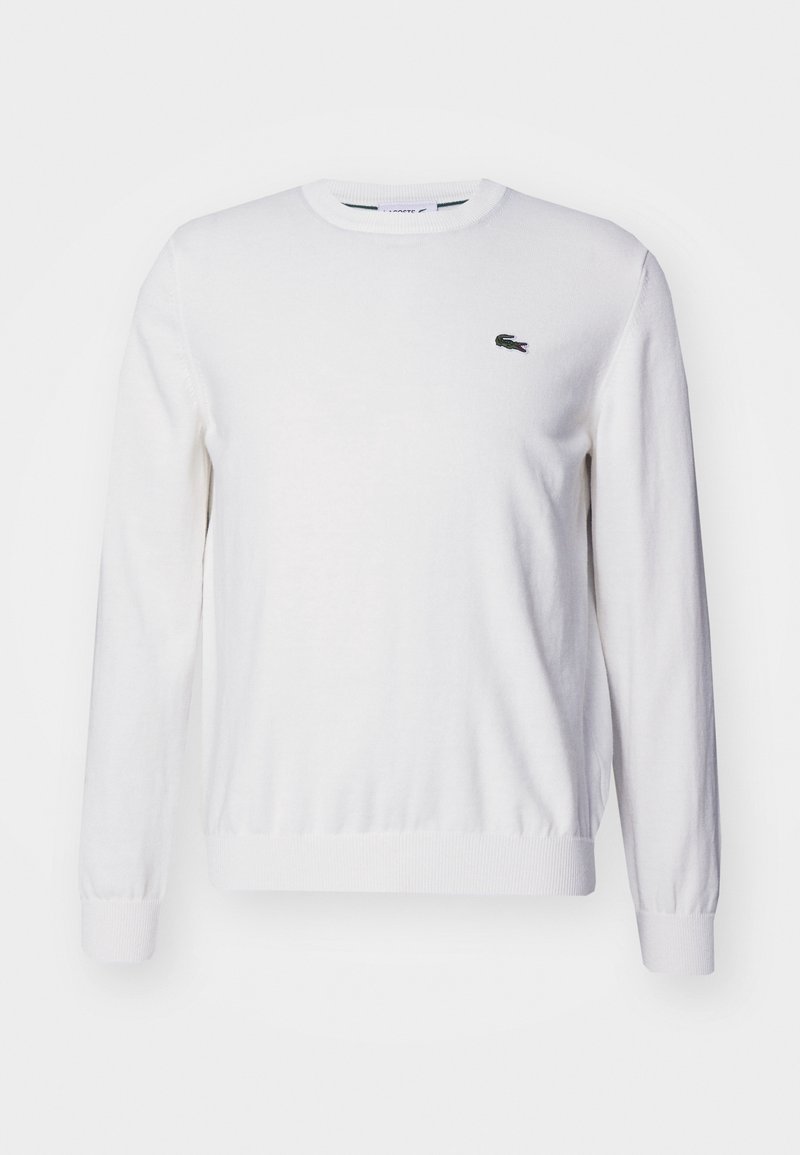 Vit bomullströja med rund halsringning och långa ärmar, med en liten broderad logotyp på bröstet samt ribbade muddar och fåll.