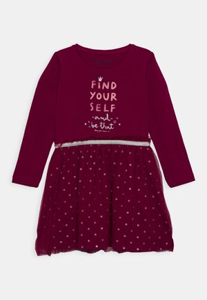 Vestido burdeos de manga larga con corsé ajustado, falda de tul con lunares plateados y cintura con acentos plateados. Texto en la parte frontal.