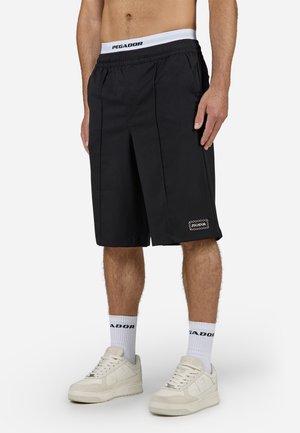 Schwarze Shorts mit einem gefalteten Design, aus leichtem Stoff gefertigt. Verfügt über einen weißen, gebrandeten Bund und ein gesticktes Logo am Saum.