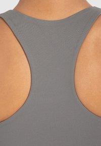 Grijze mouwloze top met een ronde halslijn, grote uitsneden bij de armopeningen, een gladde textuur en een aansluitende pasvorm.