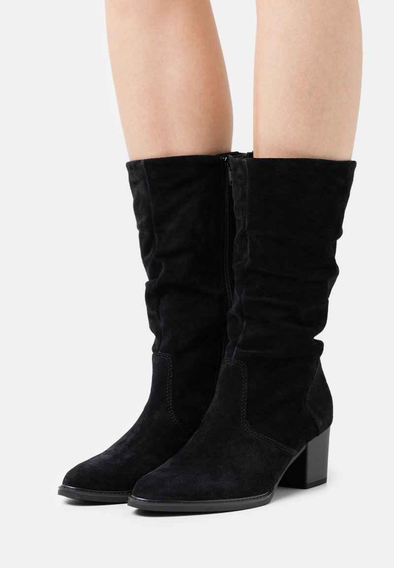 Bottes noires en daim hauteur genou avec un design décontracté, un talon bloc et une fermeture éclair sur le côté. Caractéristiques : texture lisse et bout pointu.