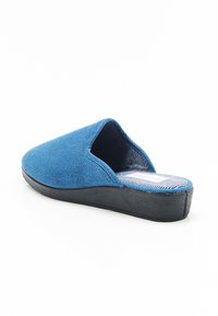 Zapatilla azul de tela tipo slip-on con punta redondeada, suela negra texturizada y forro interior a rayas. Superficie superior lisa y sin herrajes visibles.