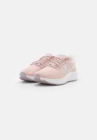 Helle pinke Sportschuhe mit einer strukturierten Oberseite, weißem Swoosh-Logo und gepolsterter Sohle. Die Schnürsenkel und die abgerundete Zehenpartie runden das Design ab.
