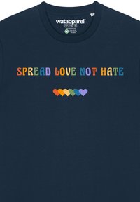 T-shirt en coton bleu marine avec des manches courtes. Le texte indique "RÉPANDRE L'AMOUR, PAS HAINE" dans des polices multicolores et ludiques au-dessus d'une rangée de cœurs colorés.