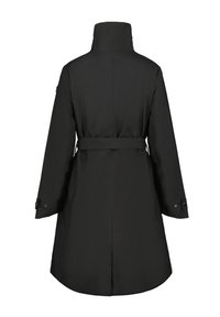Cappotto lungo nero con colletto alto, vita cintrata e polsini con bottoni; presenta una texture del tessuto liscia e una fessura posteriore per facilitare i movimenti.
