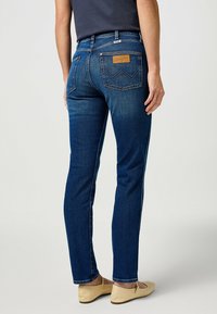 Jeans de denim de corte slim en azul oscuro, cuentan con una etiqueta de cuero con el logo, bolsillos traseros con diseño bordado y sutiles detalles en las costuras laterales.