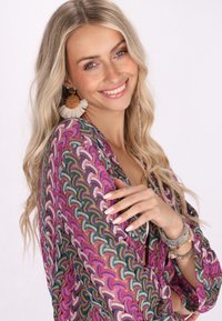 Krāsains, rakstains kimono rozā, violetā un zilā tonī ar vieglu, strukturētu audumu. Modelis valkā pērlīšu aproces un izteiksmīgas auskarus.