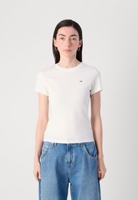 T-shirt bianco in cotone con maniche corte e scollo rotondo, caratterizzato da un piccolo logo multicolore sul lato sinistro del petto. Vestibilità casual.