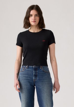 Czarny krótki t-shirt z krótkimi rękawami, w strukturalnym ribbym, z małym czerwonym logo "Levi's" na lewej piersi. Noszone z niebieskimi dżinsami z wysokim stanem.