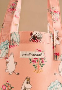 Rosa Tragetasche mit Moomin-Charakteren und Blumenmustern. Aus strapazierfähigem Material gefertigt, mit genähten Griffen und einem Logotag.