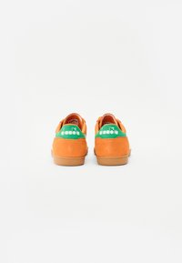 Oranje suede sneakers met een groene hielstrip met het merklogo. Gemarmerde oppervlakte en rubberen zool met contrasterende details.