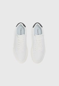 Nike sport cu un superior din material textil neted și un toc texturat negru. Prezintă șireturi albe și un logo subtil pe interiorul tălpii.