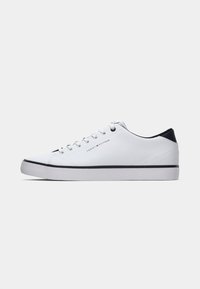 Bijeli niskoprofilni tenisice s crnim detaljem na peti, bijelim vezicama i crnom prugom na potplatu, oznakom Tommy Hilfiger logotipom na strani.